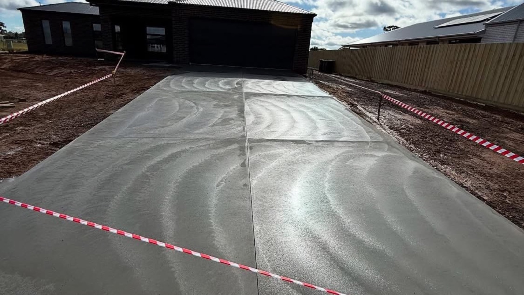 A freshly finished concrete driveway taped off in front of a home