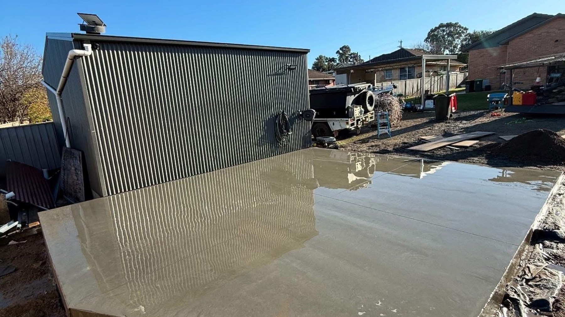 A wide concrete slab poured up against a corrugated shed wall