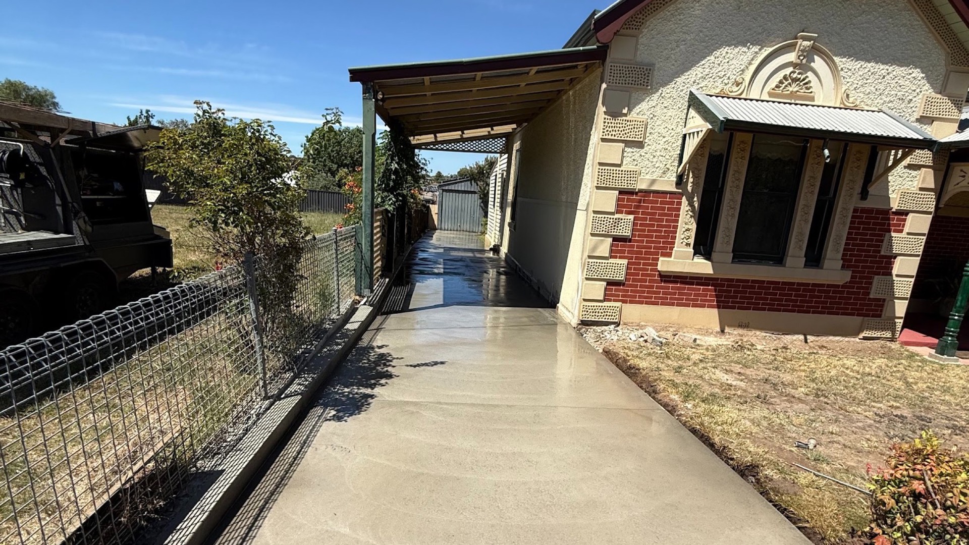 A concrete driveway running past the verandah of a goldfields-era brick and stone home