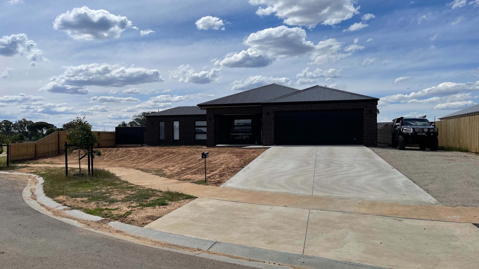 A wide plain concrete driveway running up to a dark brick home in Bendigo