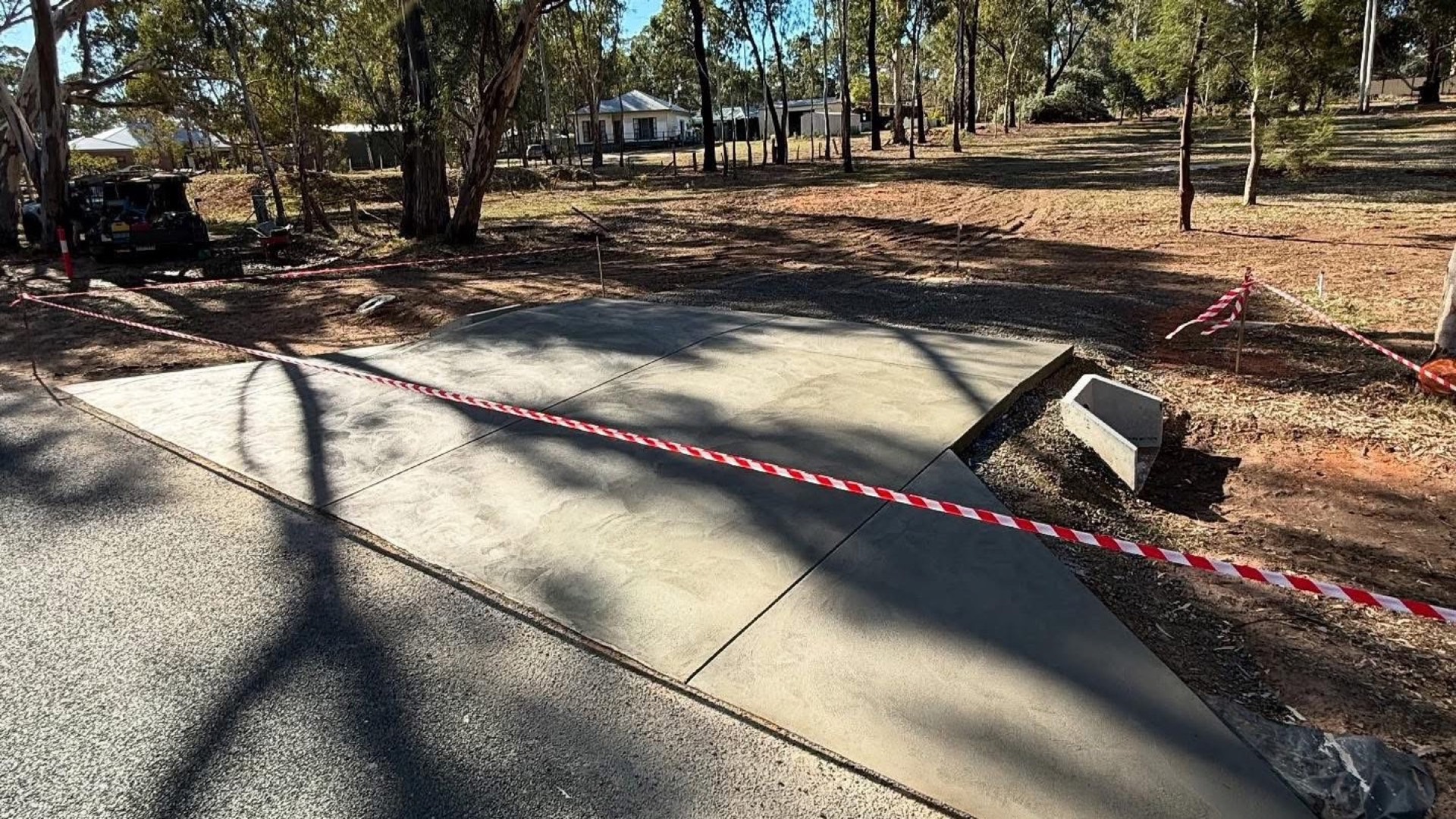 A concrete driveway under dappled shade from box-ironbark gums