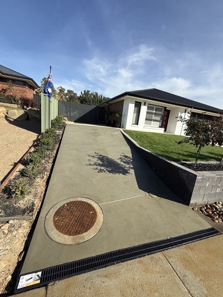 A curved driveway with a formed edge running past a garden bed