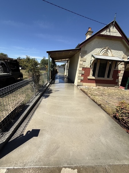 A concrete driveway running past the verandah of a goldfields-era brick home
