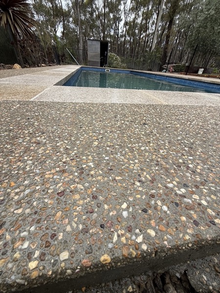 Close detail of a washed exposed aggregate surface beside a pool edge