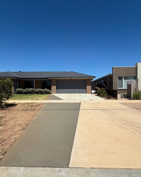 A wide plain concrete driveway leading to a double garage