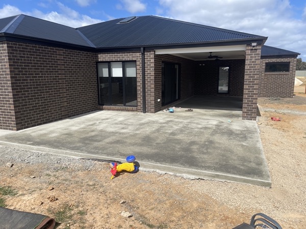 A concrete driveway and apron poured in front of a brick home