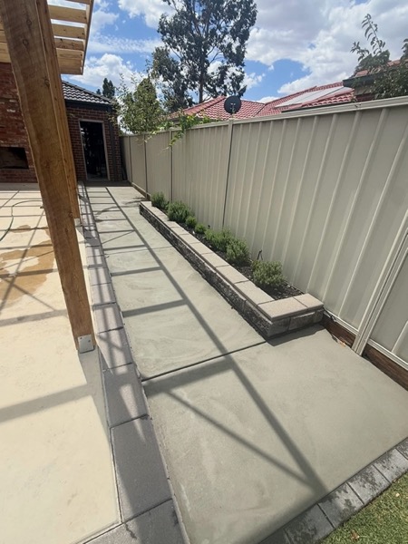 A concrete path stepping down beside a garden bed and retaining edge