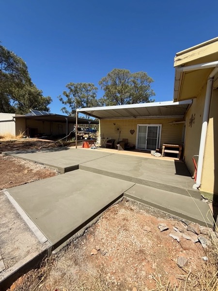 Concrete paths and a driveway wrapping around a cream rendered home
