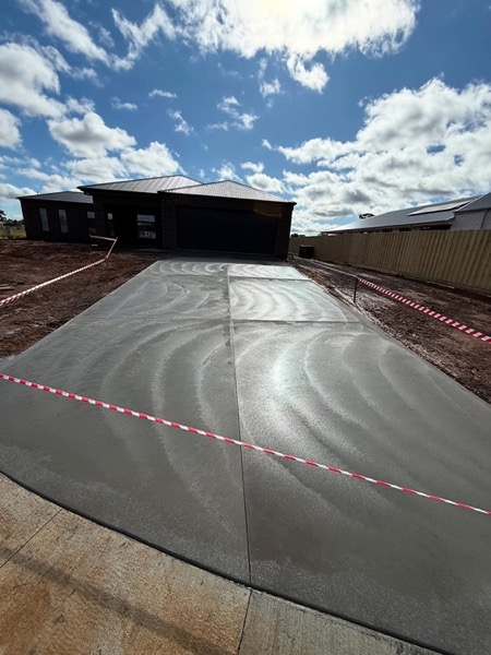 A freshly finished concrete driveway taped off in front of a home