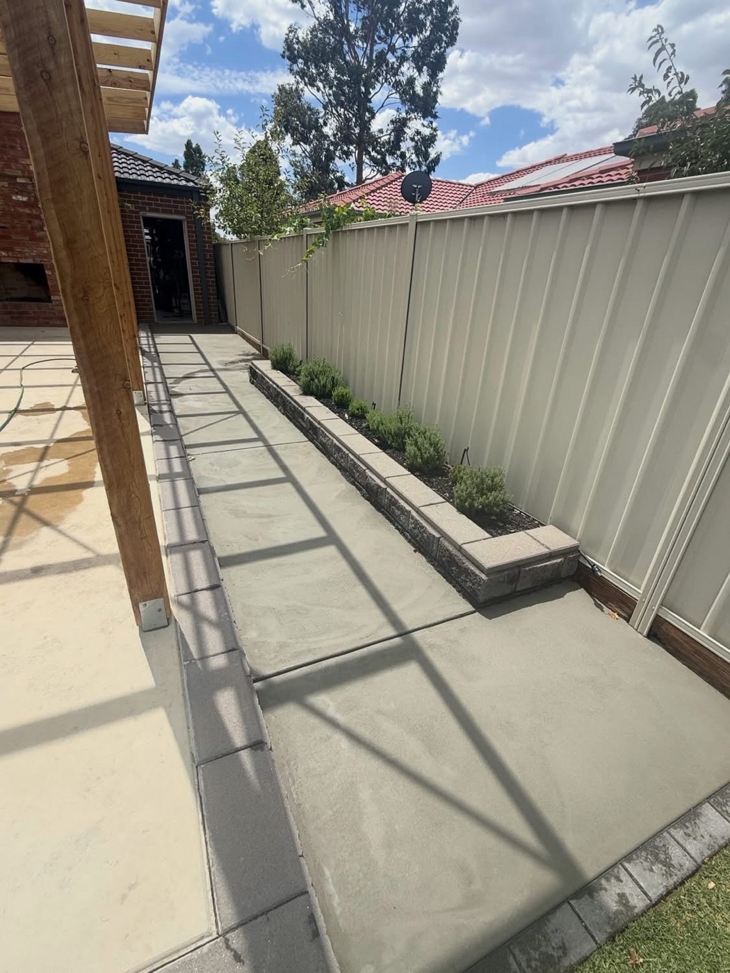 A concrete path stepping down beside a garden bed and retaining edge